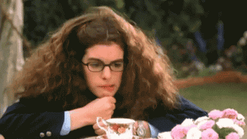 Anne Hathaway in &quot;The Princess Diaries leaning on her fist blowing a strand of hair in the air