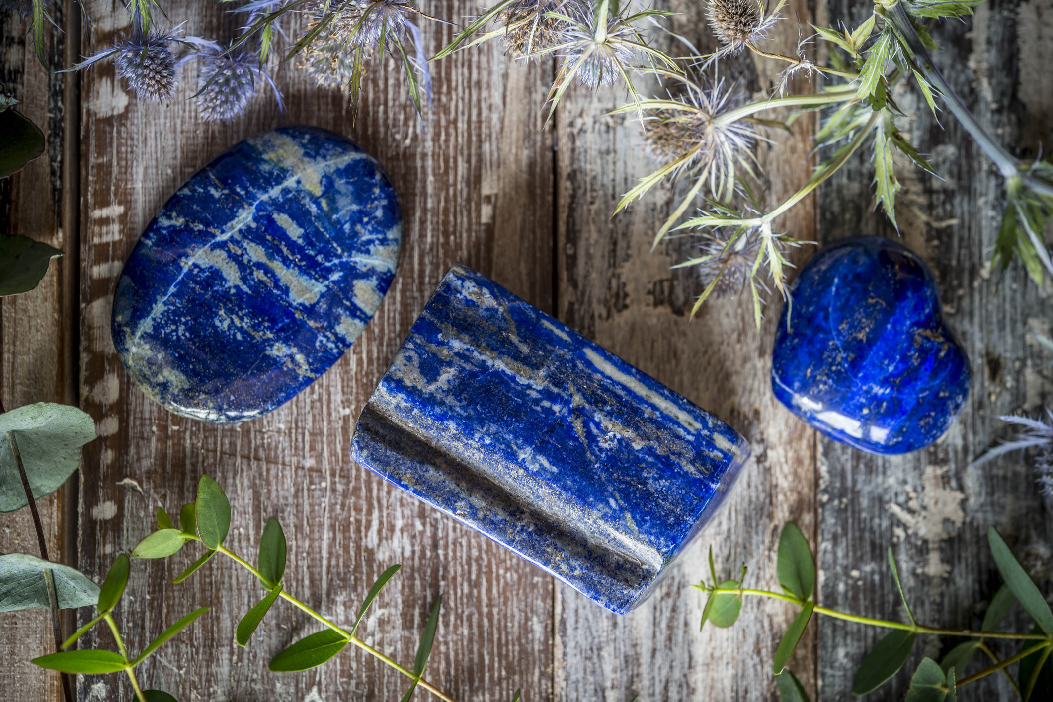 Lapis lazuli surrounded by thistles, Eucalyptus on a rustic wooden background