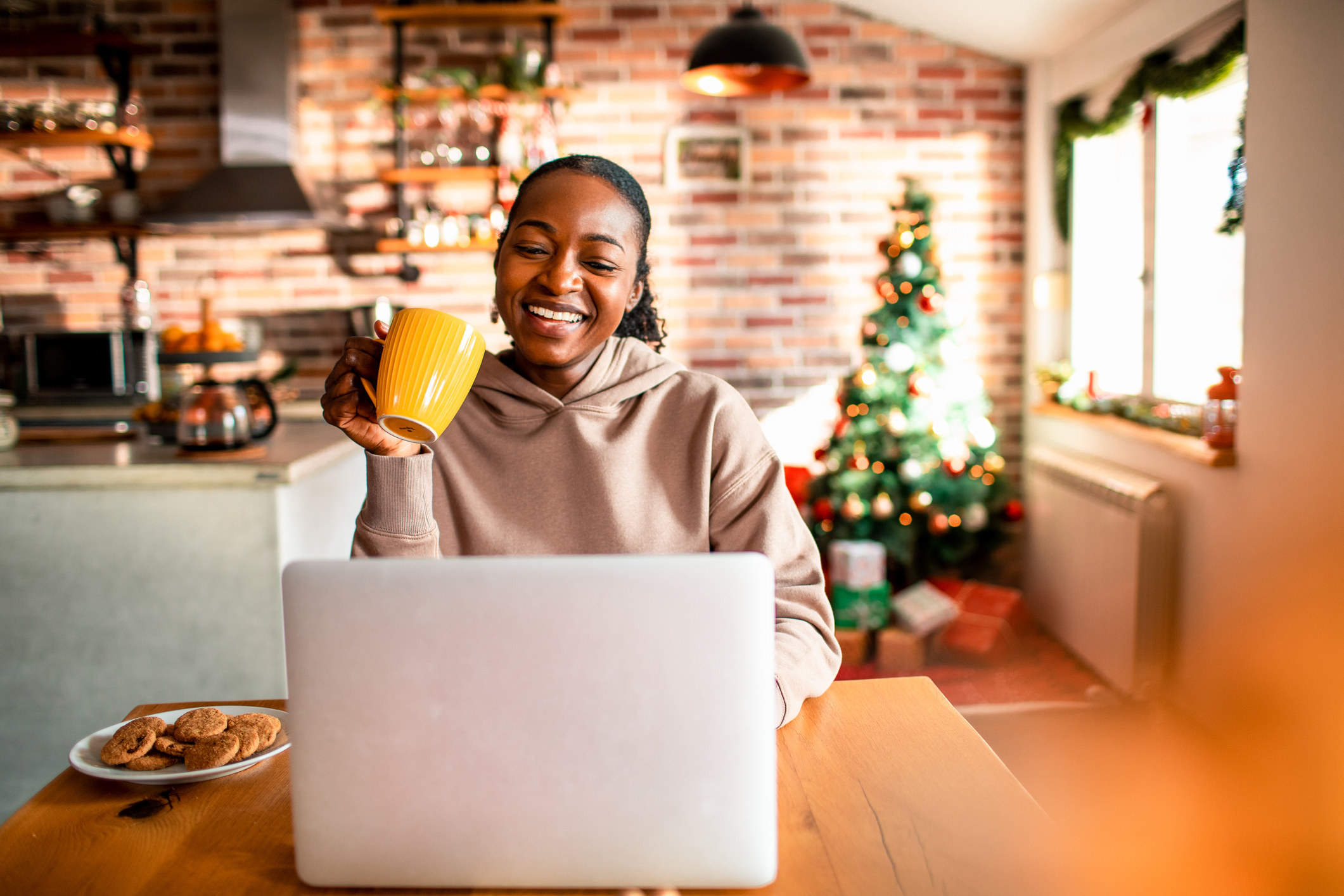 Woman using her laptop and drinking coffee in a home decorated for the holidays