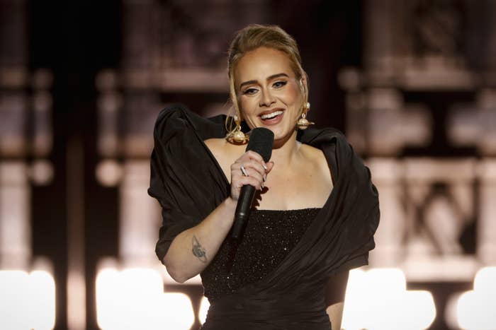Adele holds a microphone onstage