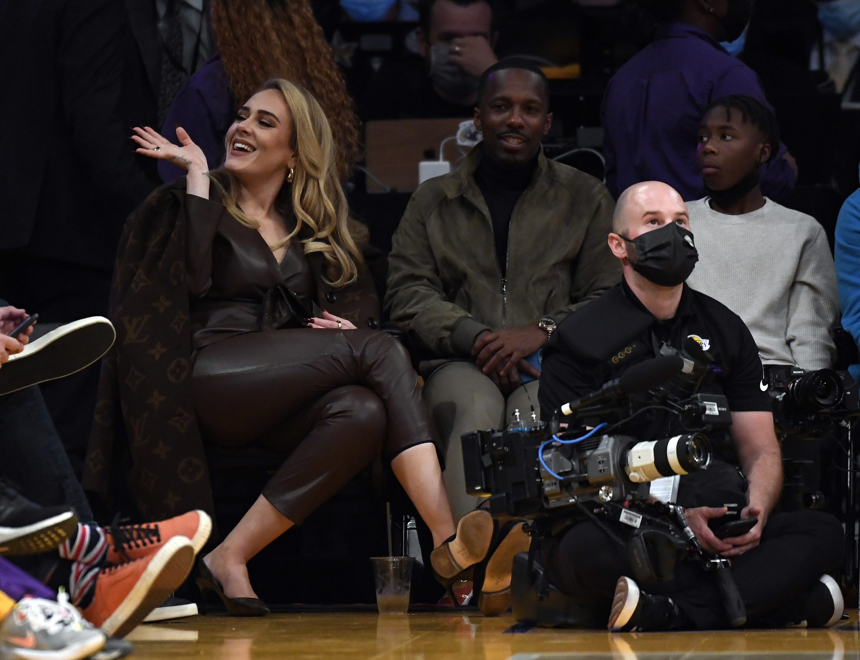 Adele waves to someone over her shoulder at a basketball game