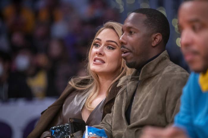 Adele bares her teeth while sitting next to Rich Paul courtside