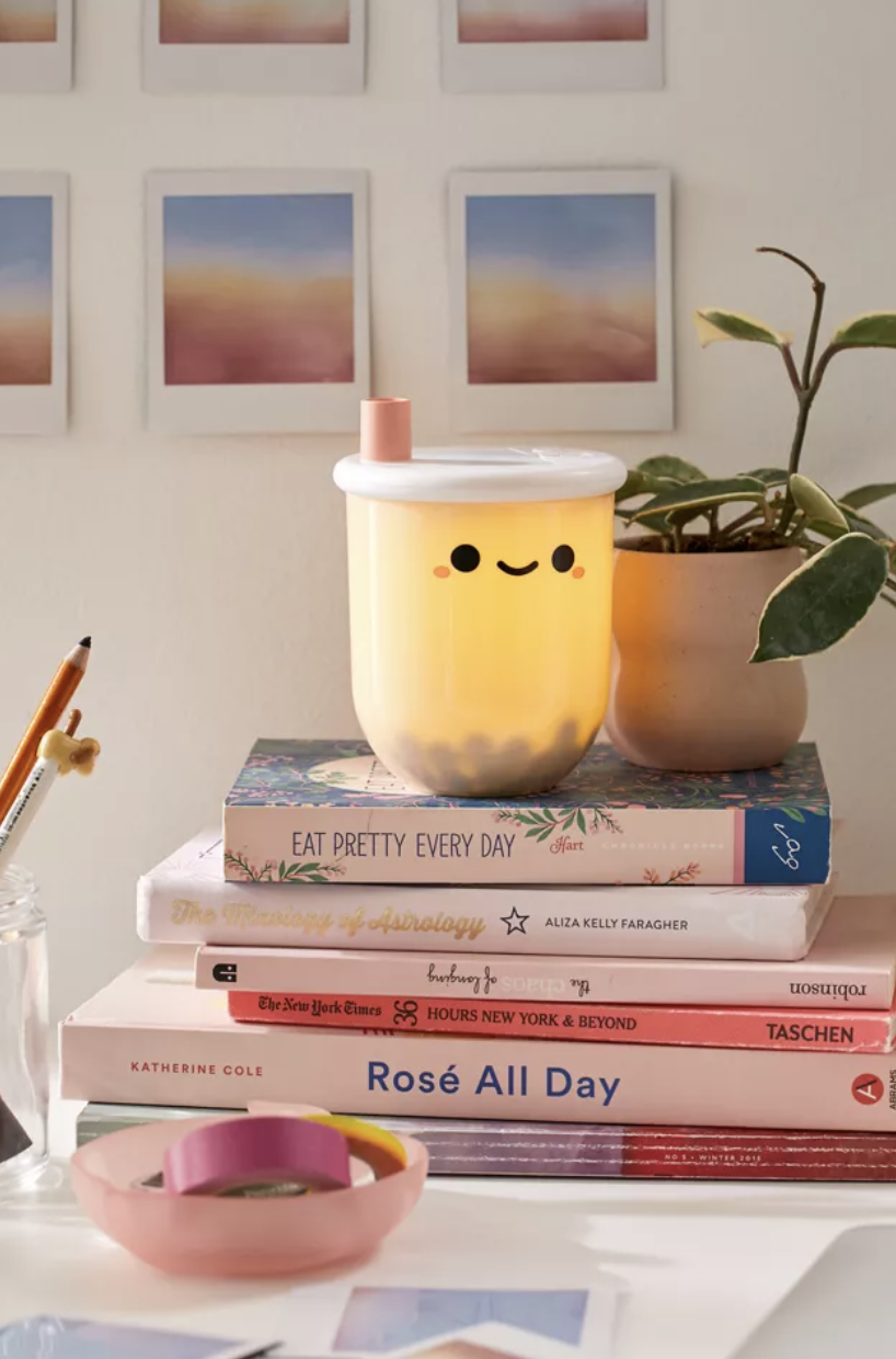 Bubble tea-shaped light sitting on stack of books on desk