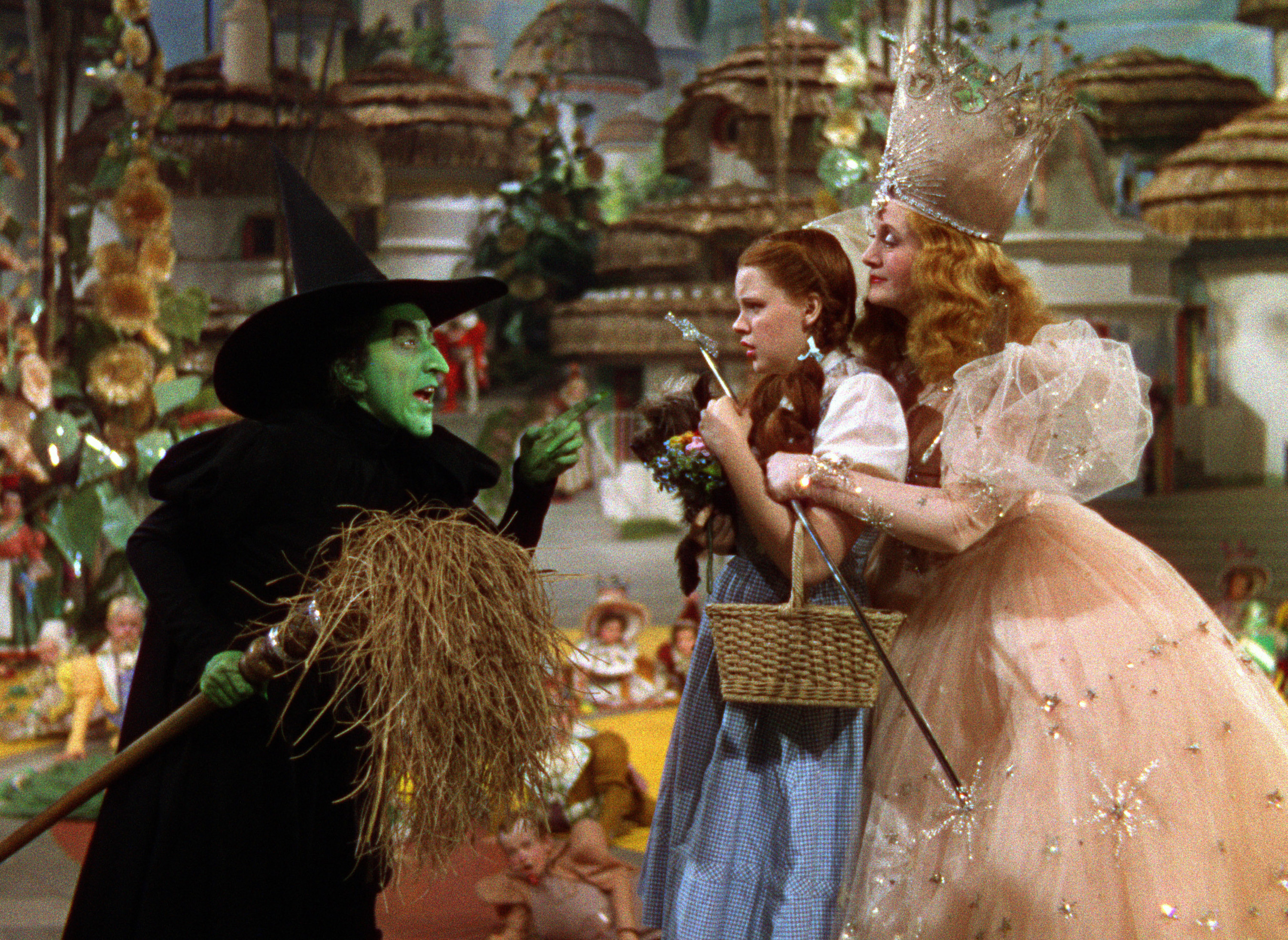 The Wicked Witch of the West threatening Dorothy as Glinda holds her