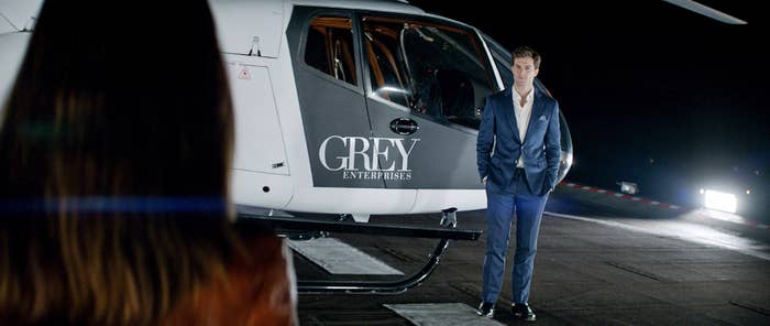 Dornan stands in front of a helicopter looking at Dakota Johnson