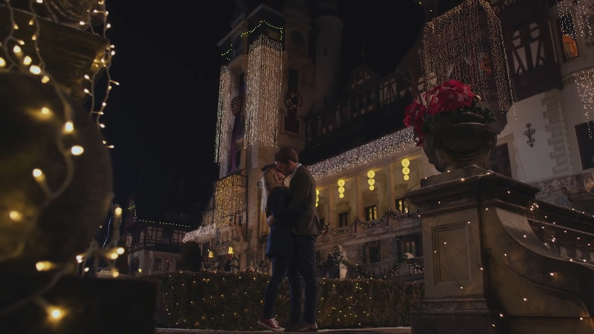 A man and a woman kiss in the garden of a castle