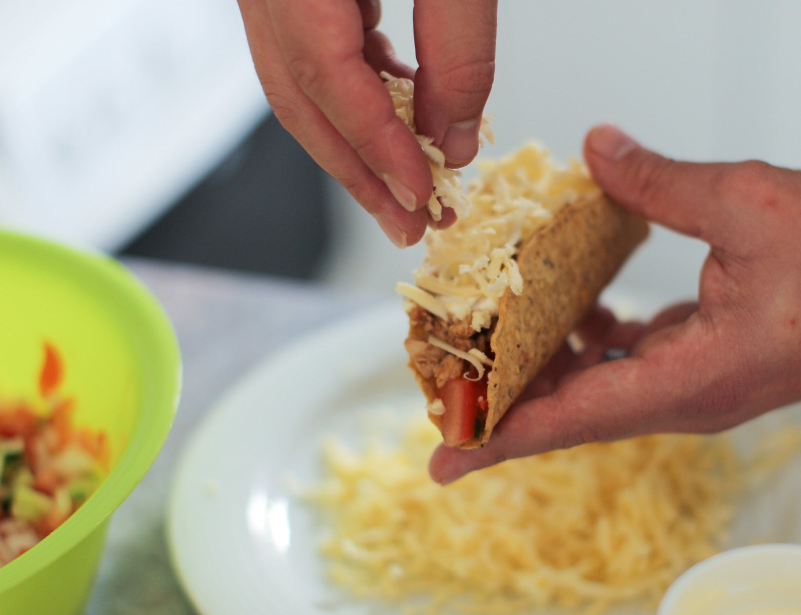 Sprinkling cheese onto a taco.