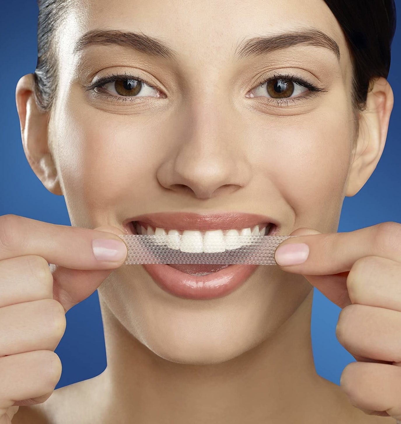 A person putting a strip on their teeth