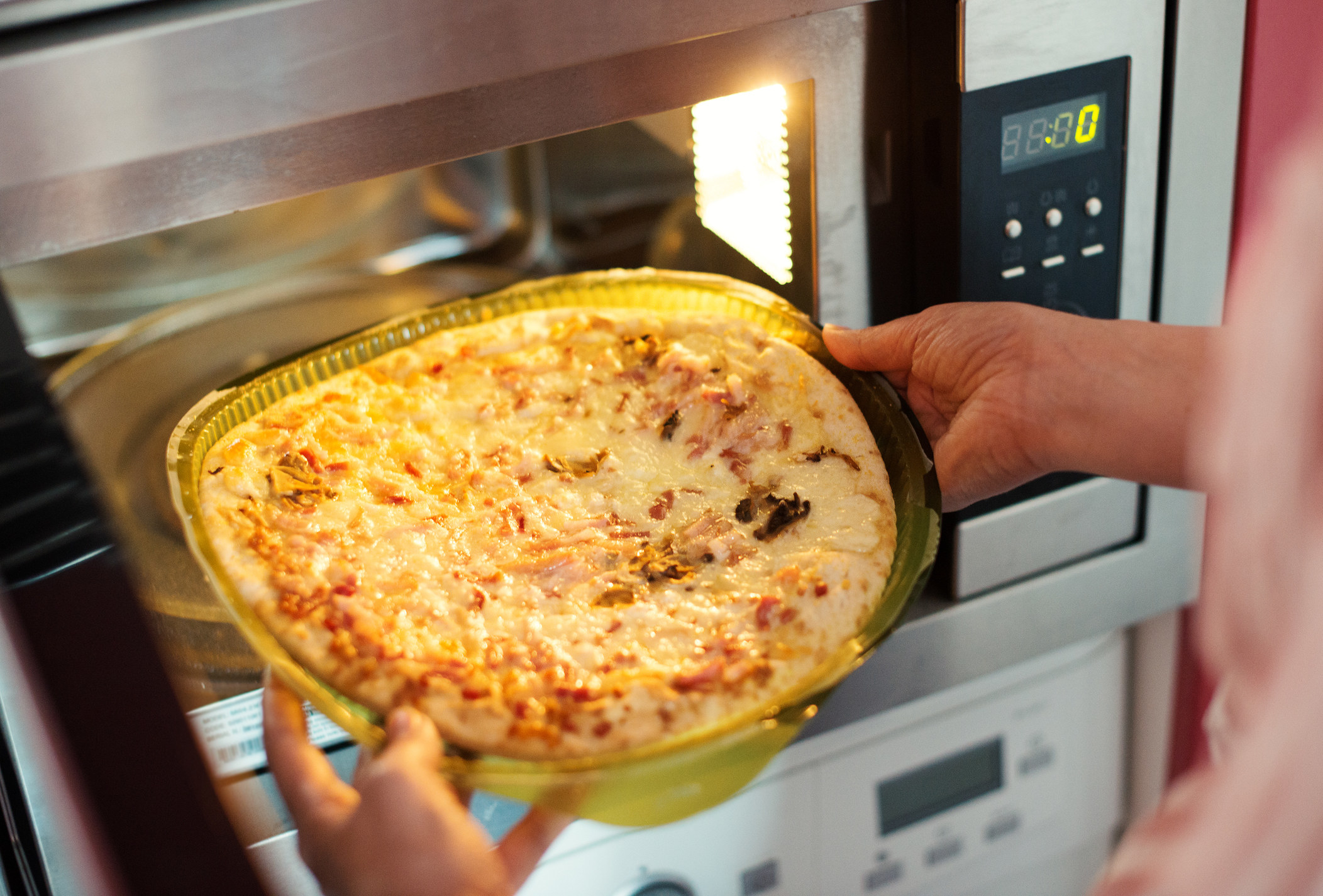 A woman making pizza in the microwave.