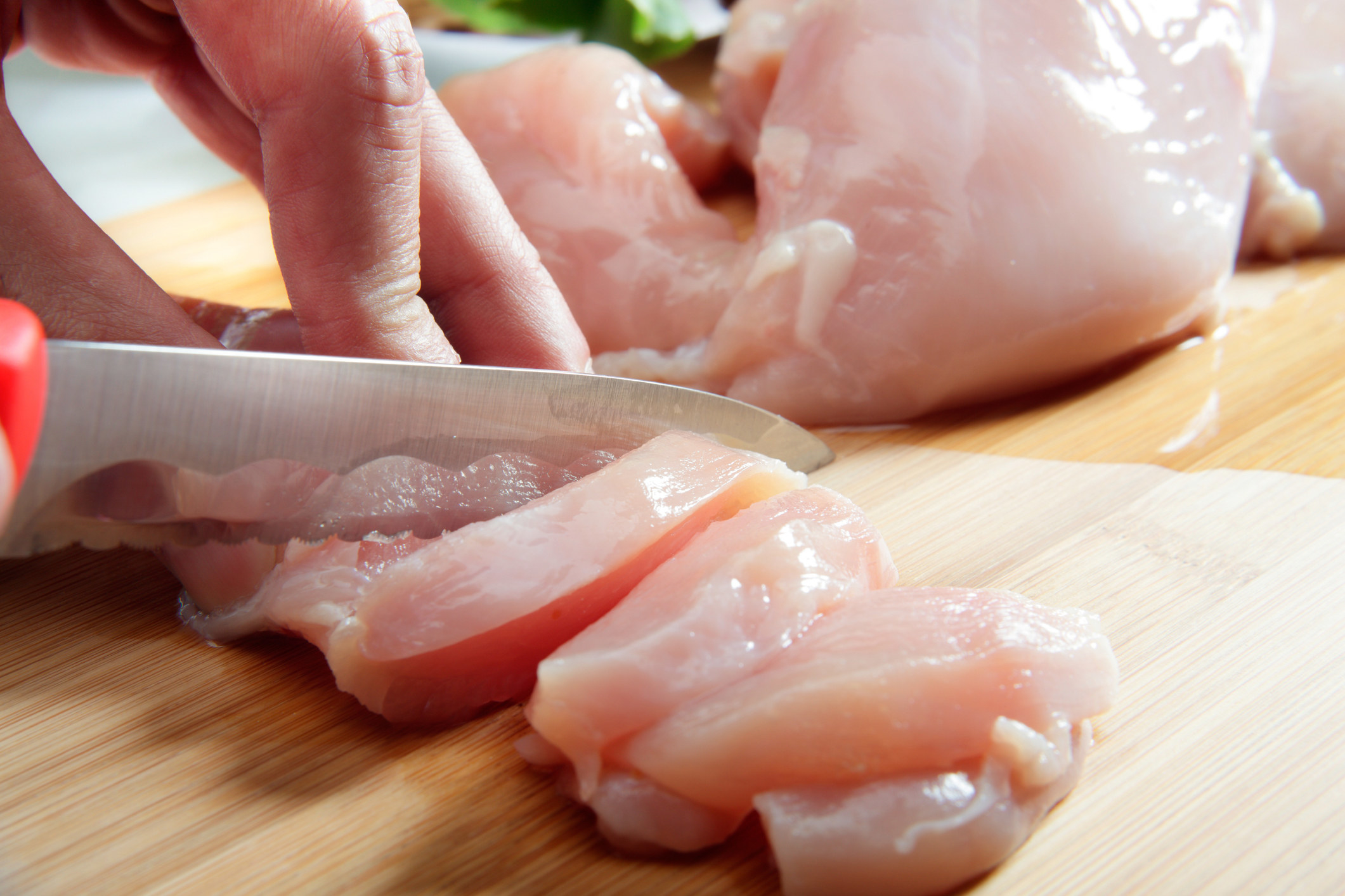 Slicing raw chicken.
