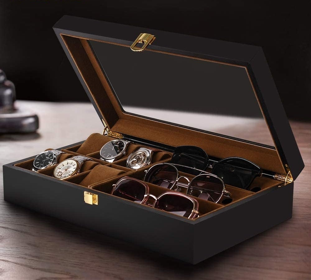 an open accessory box filled with watches and sunglasses