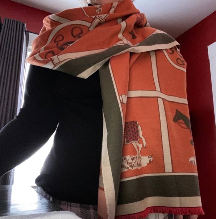 Reviewer wearing large orange scarf with horse details