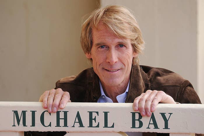 Michael Bay standing behind a sign that reads Michael Bay