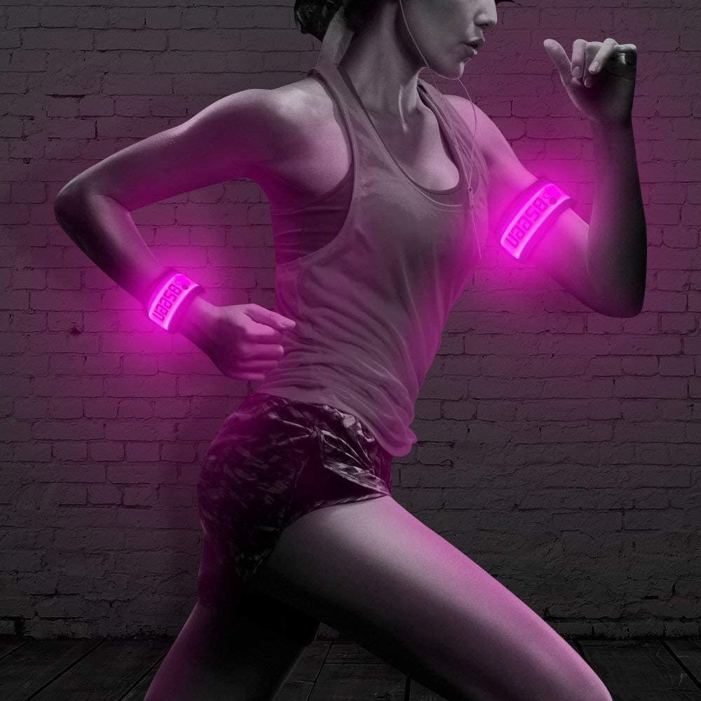 model running at nighttime with pink LED arm bands on their wrists