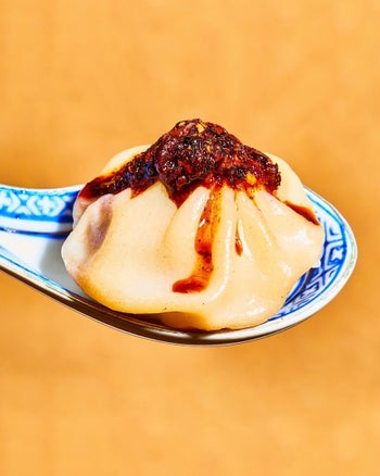 A soup dumpling topped with the chili crisp on a spoon