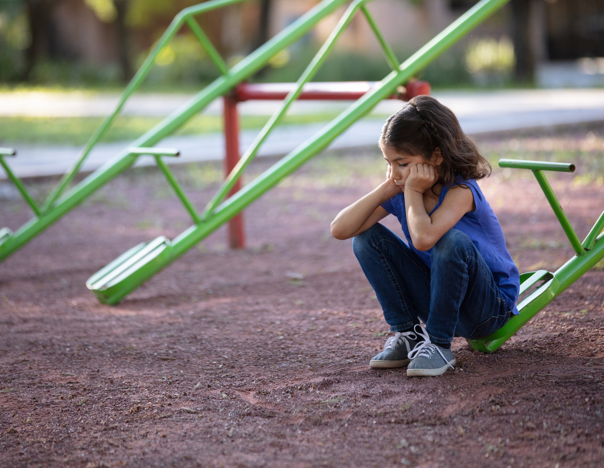 A little girl sitting on a seesaw by herself