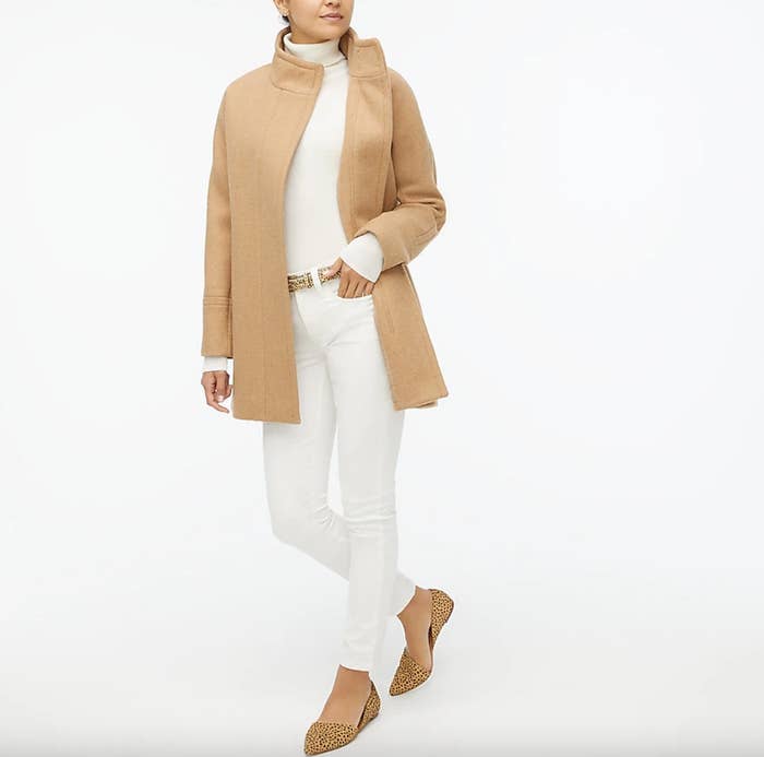 model wearing a camel coat and white pants and shirt