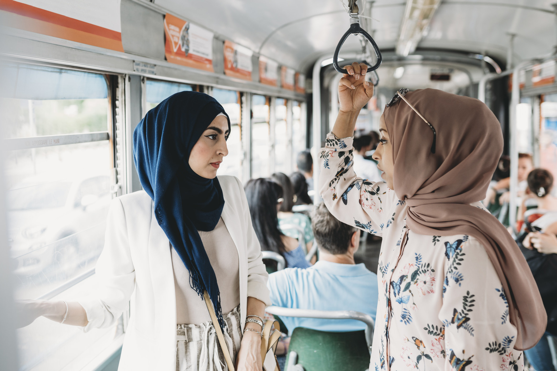 Two Muslim women talking to each other on a bus