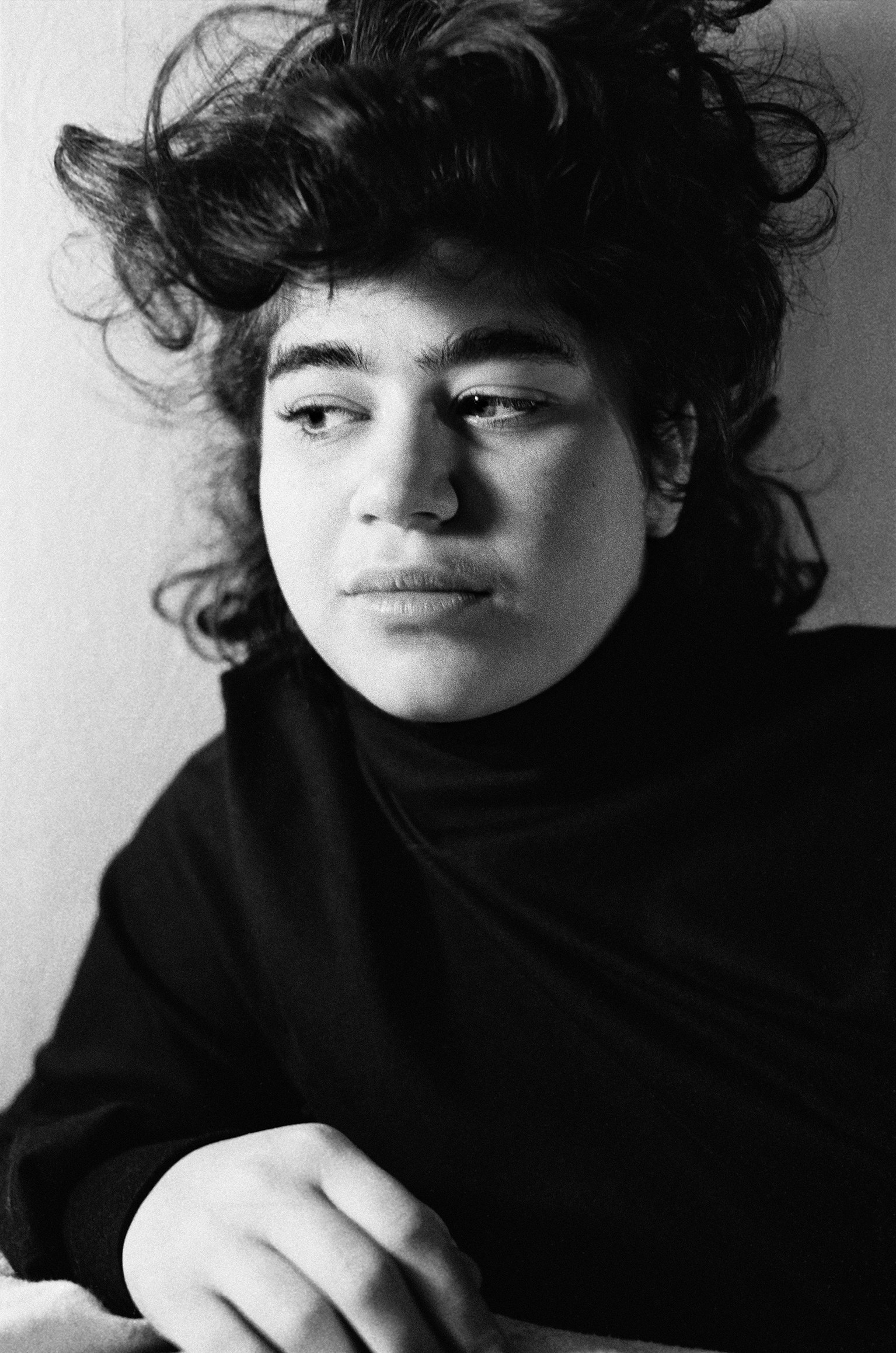 A young girl with curly hair named Molly wears a black turtleneck and looks off to the side of the camera 
