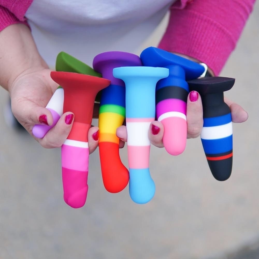Model holding assortment of striped dildos and plugs
