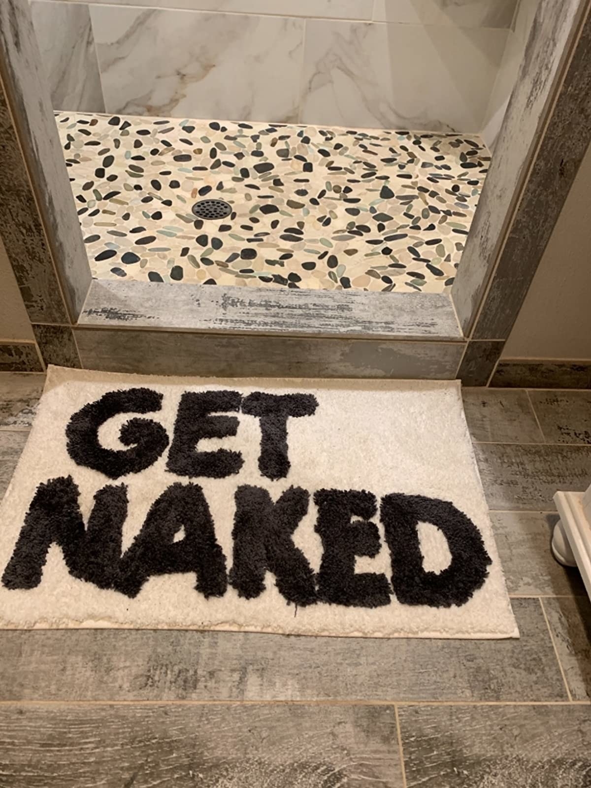 Reviewer image of black and white bath mat in front of shower that says &quot;get naked&quot;