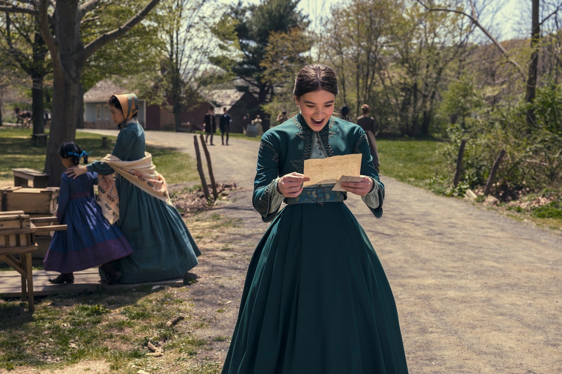 still of Emily in Dickinson walking through town while smiling at a letter