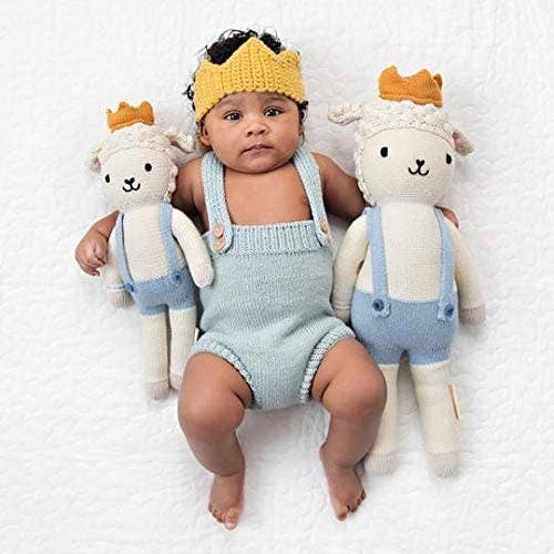 baby beside one large and one small dressed lamb doll. both dolls have on crowns.