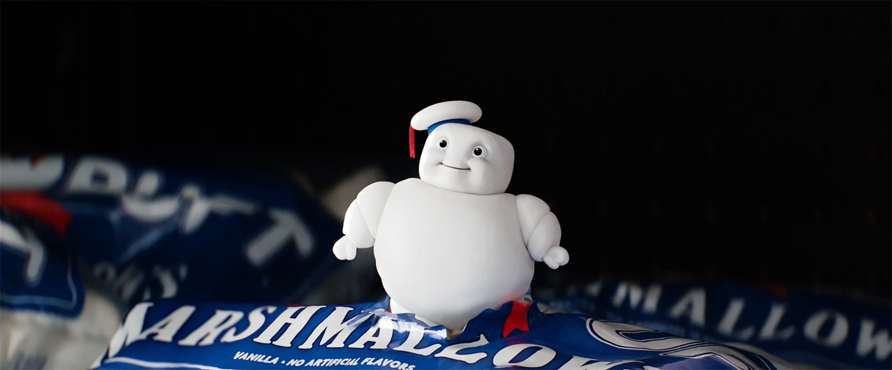 A tiny Stay Puft marshmallow man bursting out of a mini package of marshmallows