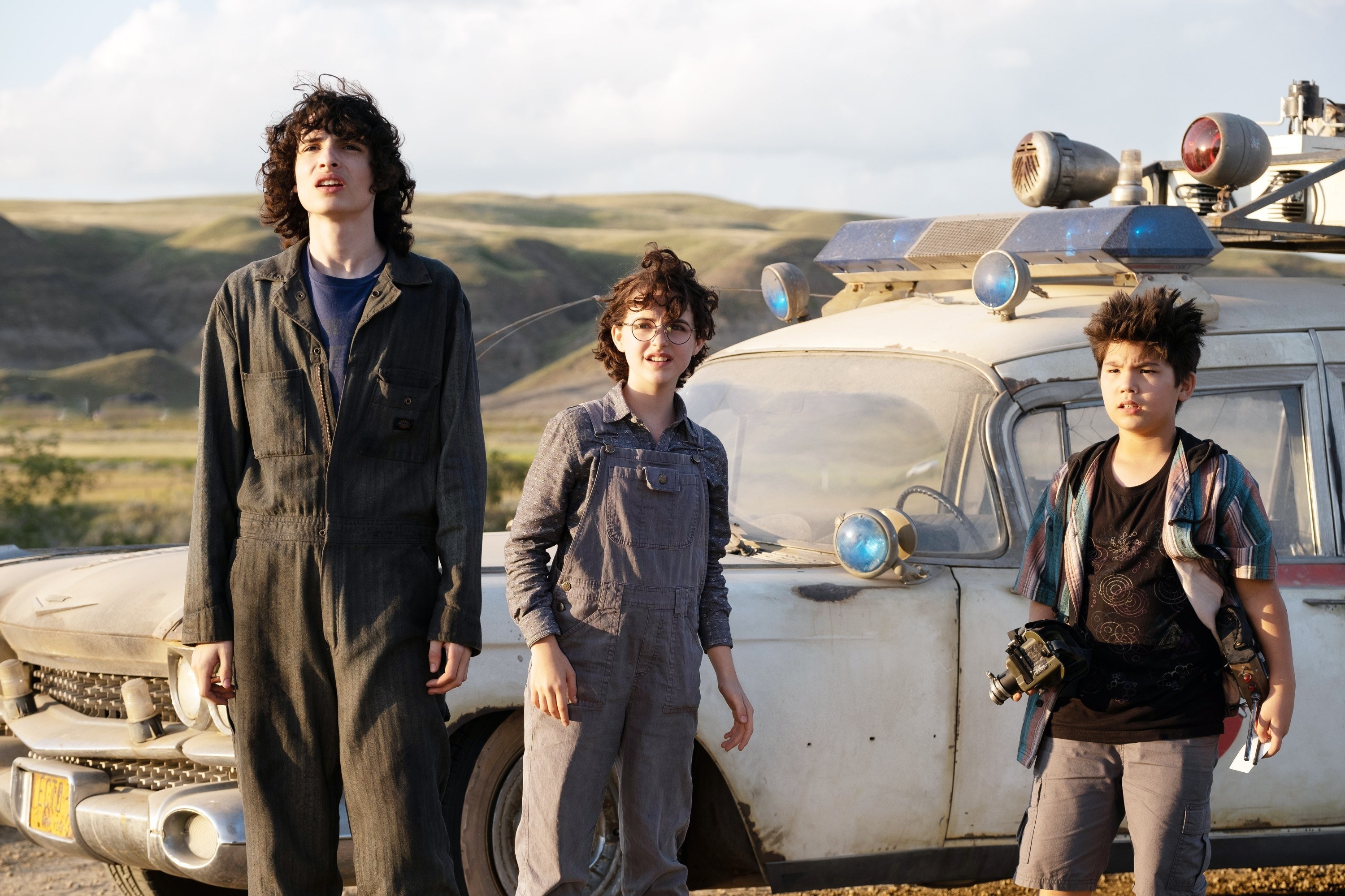 The kids standing in front of the Ecto-1 in the middle of nowhere looking up at something