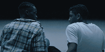 Childhood friends Chiron and Kevin, played by Ashton Sanders and Jharrel Jerome, lean in for a kiss at night in &quot;Moonlight&quot;