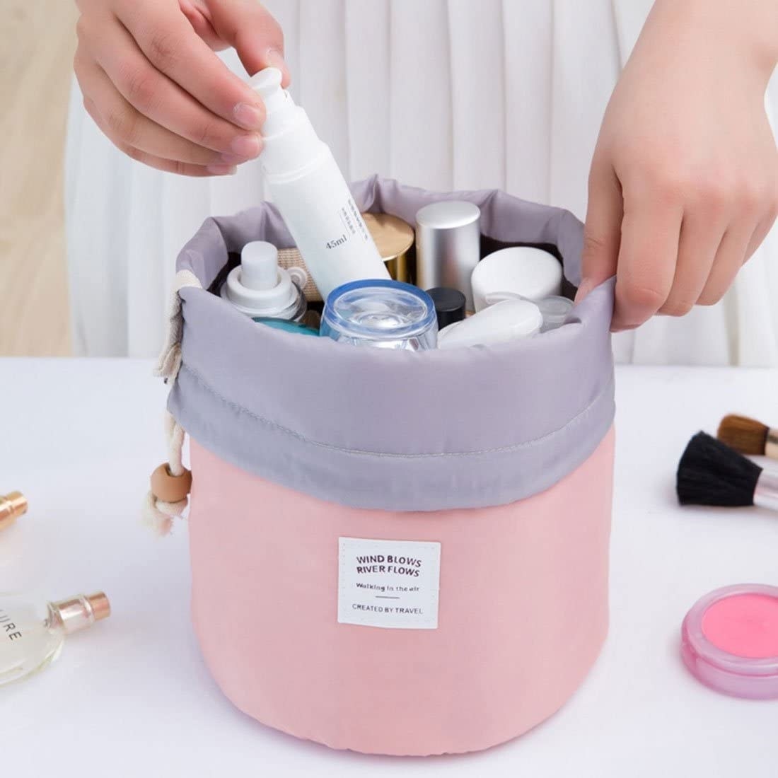 someone putting products into the bucket-shaped drawstring cosmetics bag