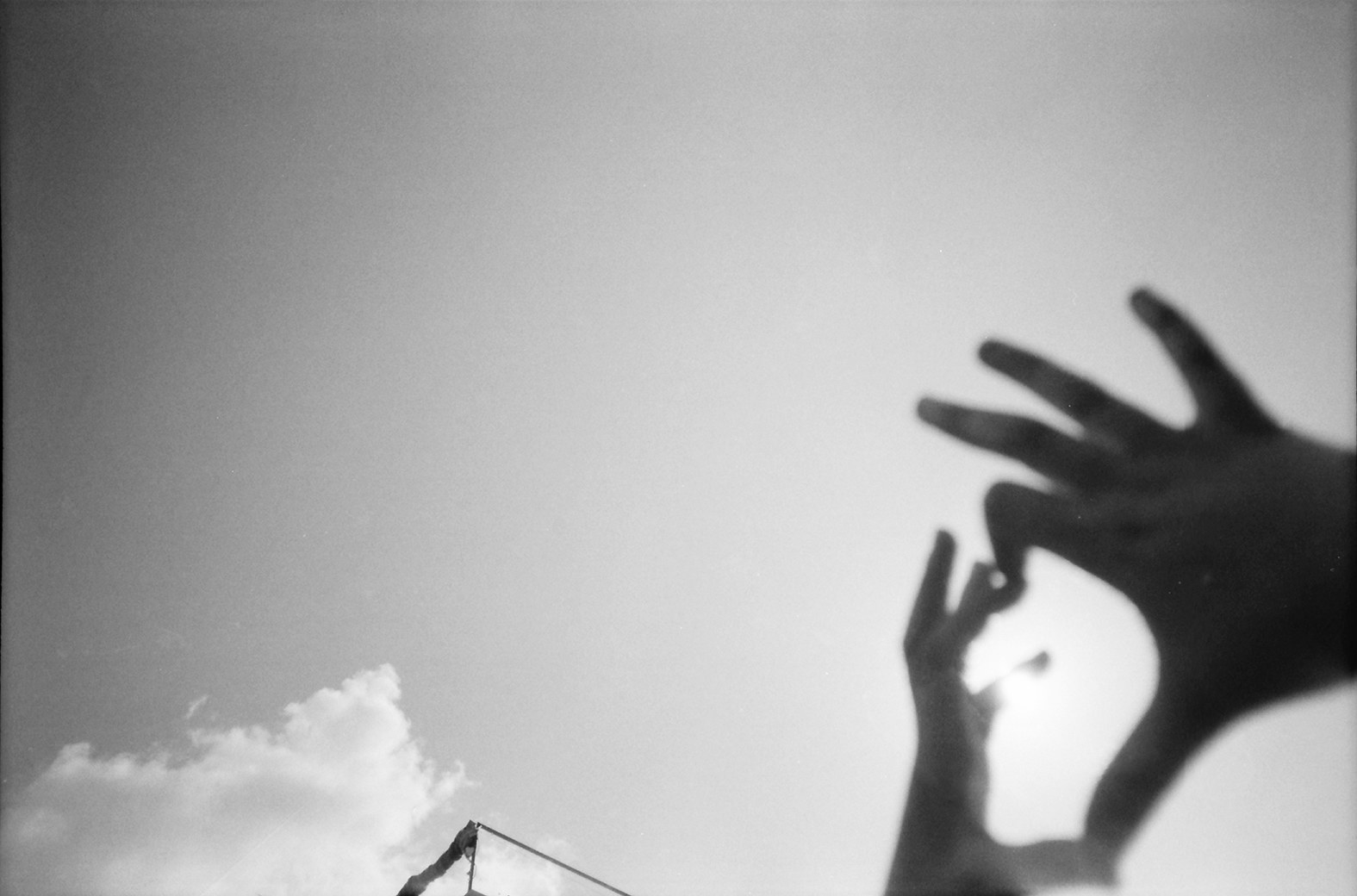 Hands make a shape in the air with clouds in the background