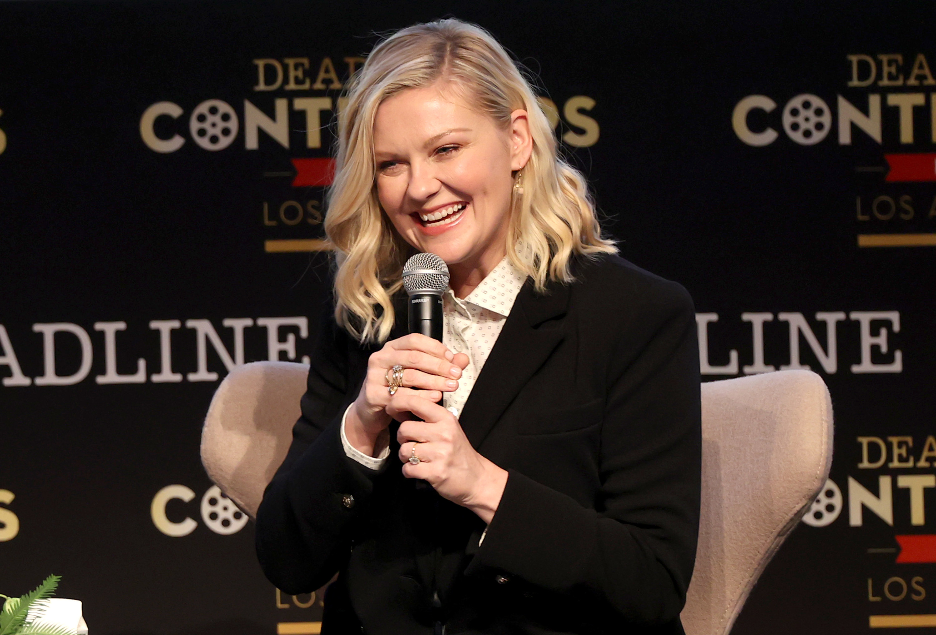 Photo of Kirsten Dunst sitting in a chair with a microphone