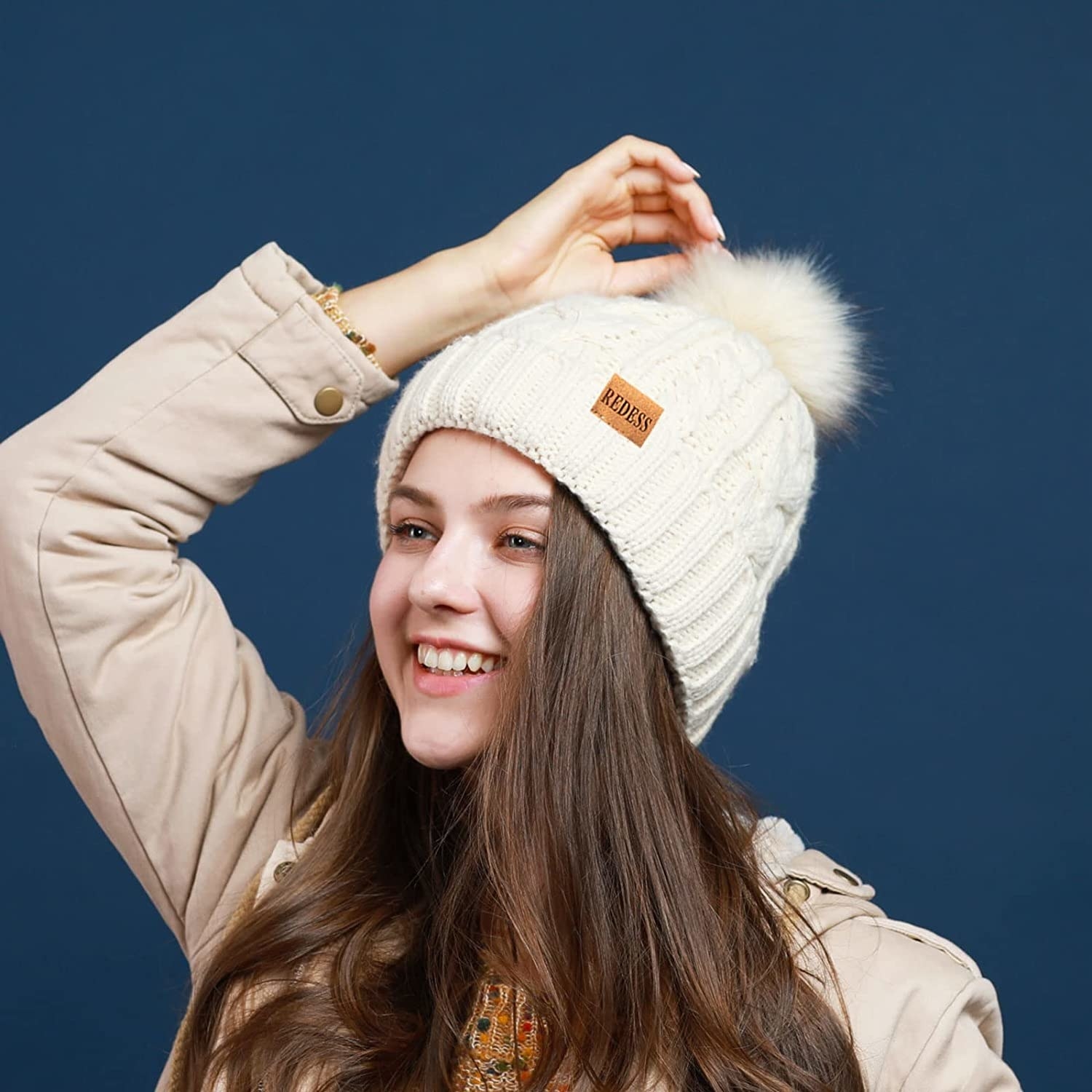a smiling person wearing the cable knit beanie