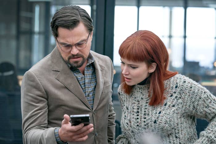 Jennifer and Leonardo look at a phone in the movie