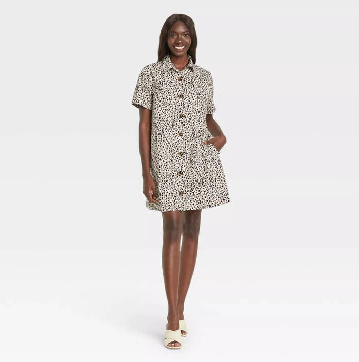 model wearing the shirt dress with white and black patterns and white sandals