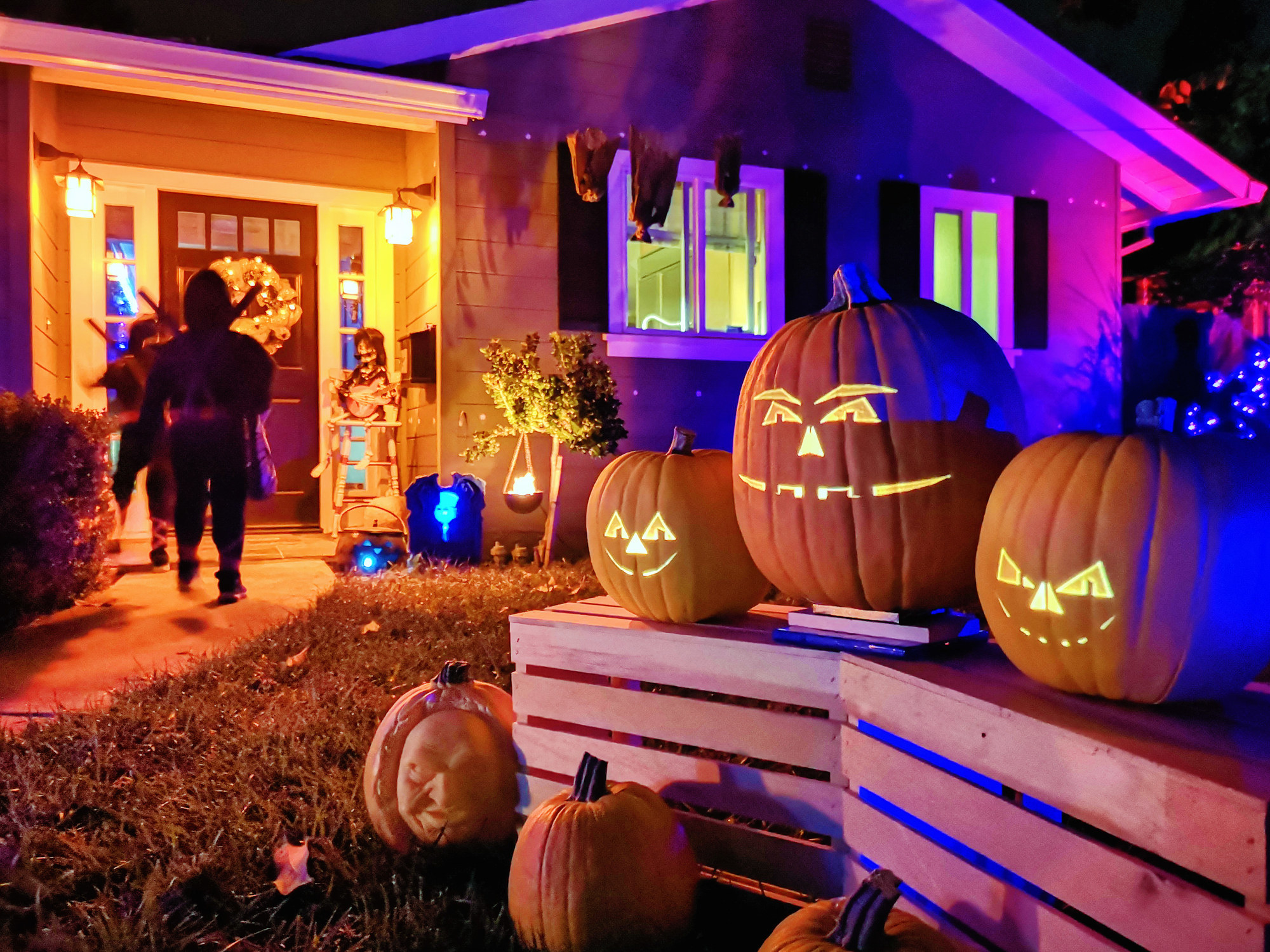 Kids trick-or-treating on Halloween night in suburban Californian house decorated with jack-o&#x27;-lantern