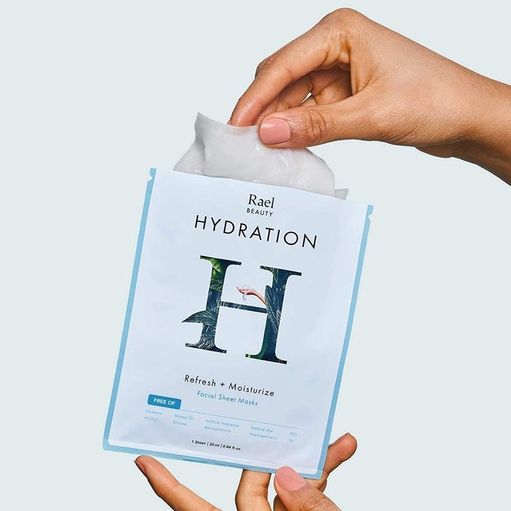 a person removing the sheet mask from the packet