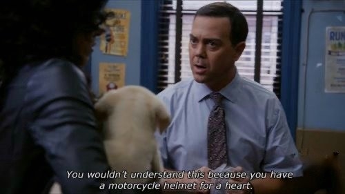 Joe Lo Truglio, playing his character as Charles Boyle, dressed in a light blue shirt with a tie, in conversation with Stephanie Beatriz