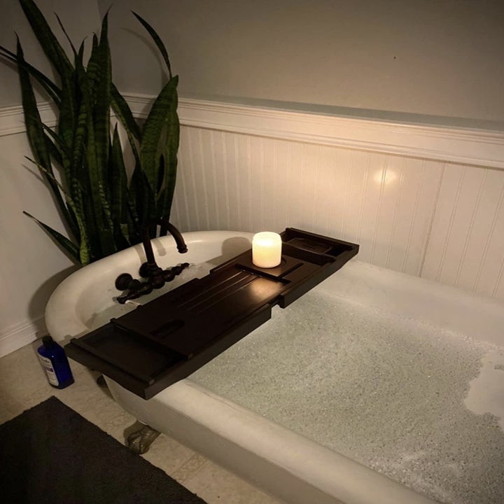 the bamboo tray in dark brown resting over a bath