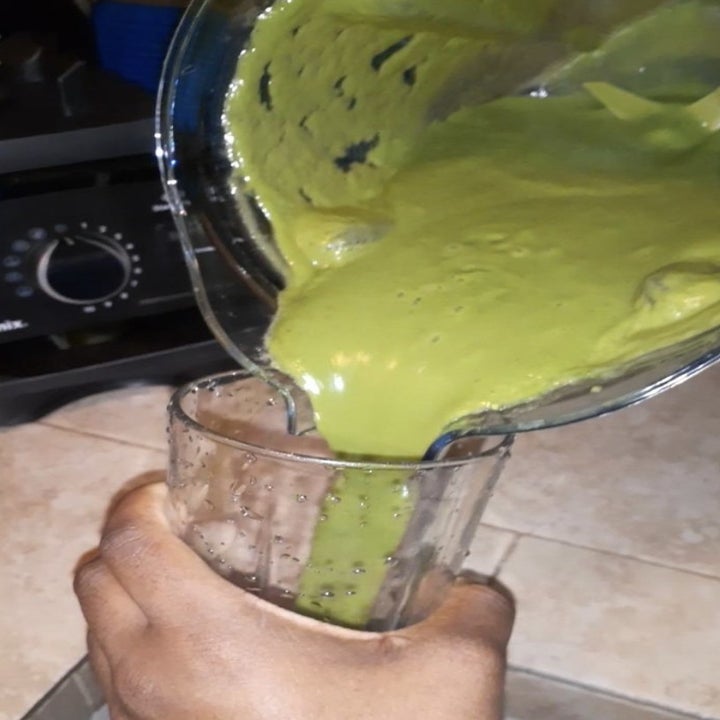 a photo of a person pouring their smoothie into a cup