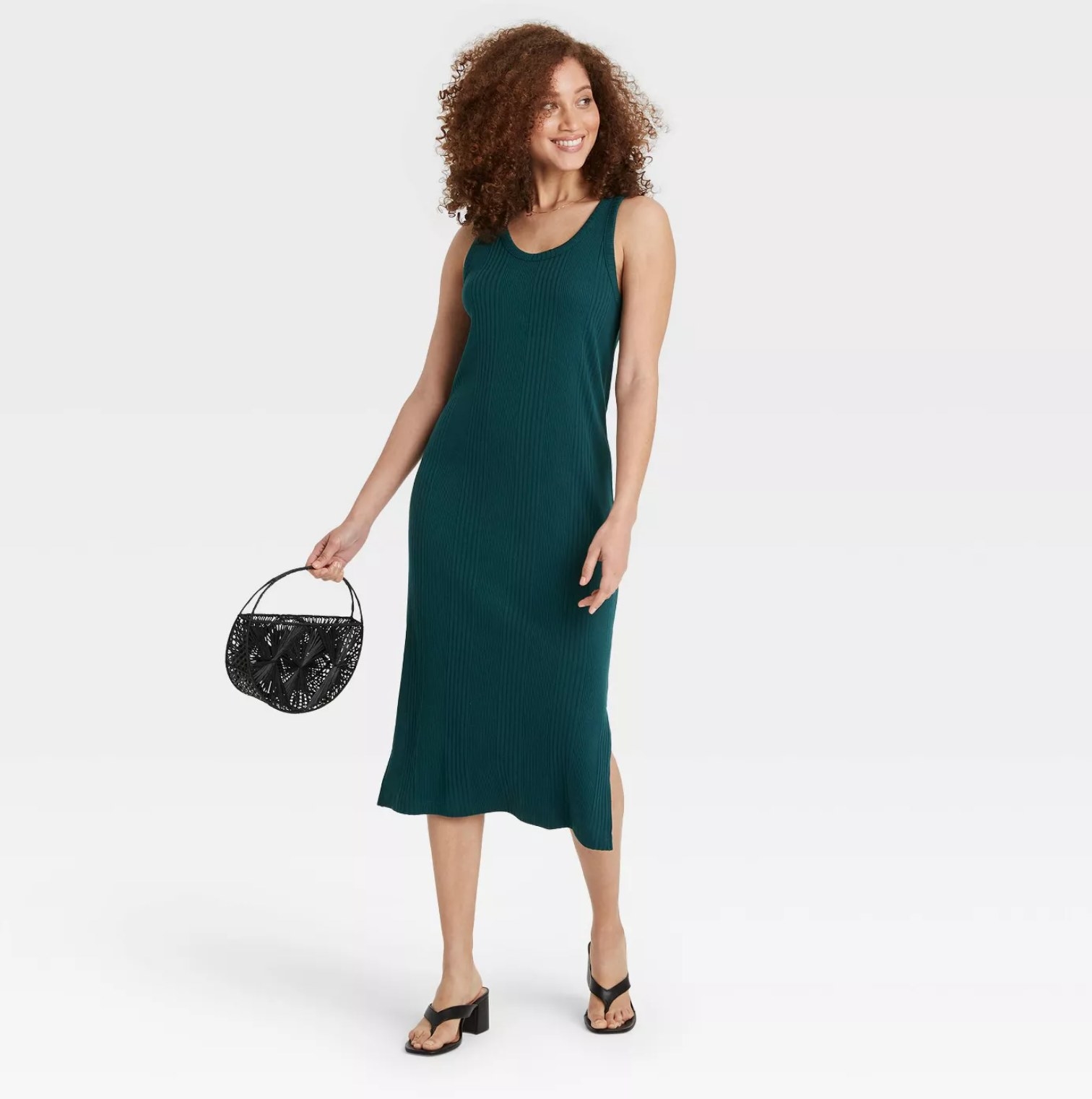 model wearing the ribbed dress in green with black flip flops carrying a black handbag