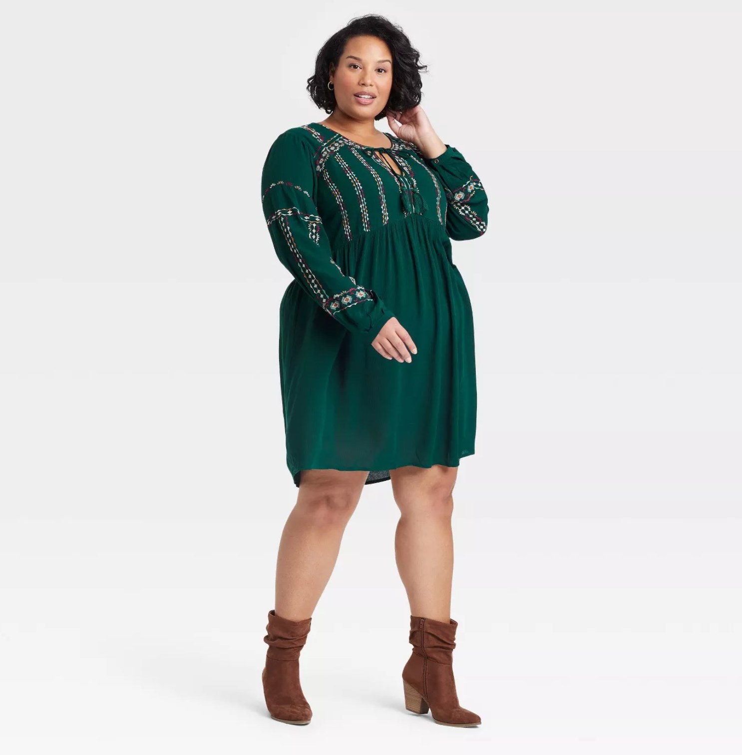 model wearing the dress in green with an embroidered top and brown ankle booties