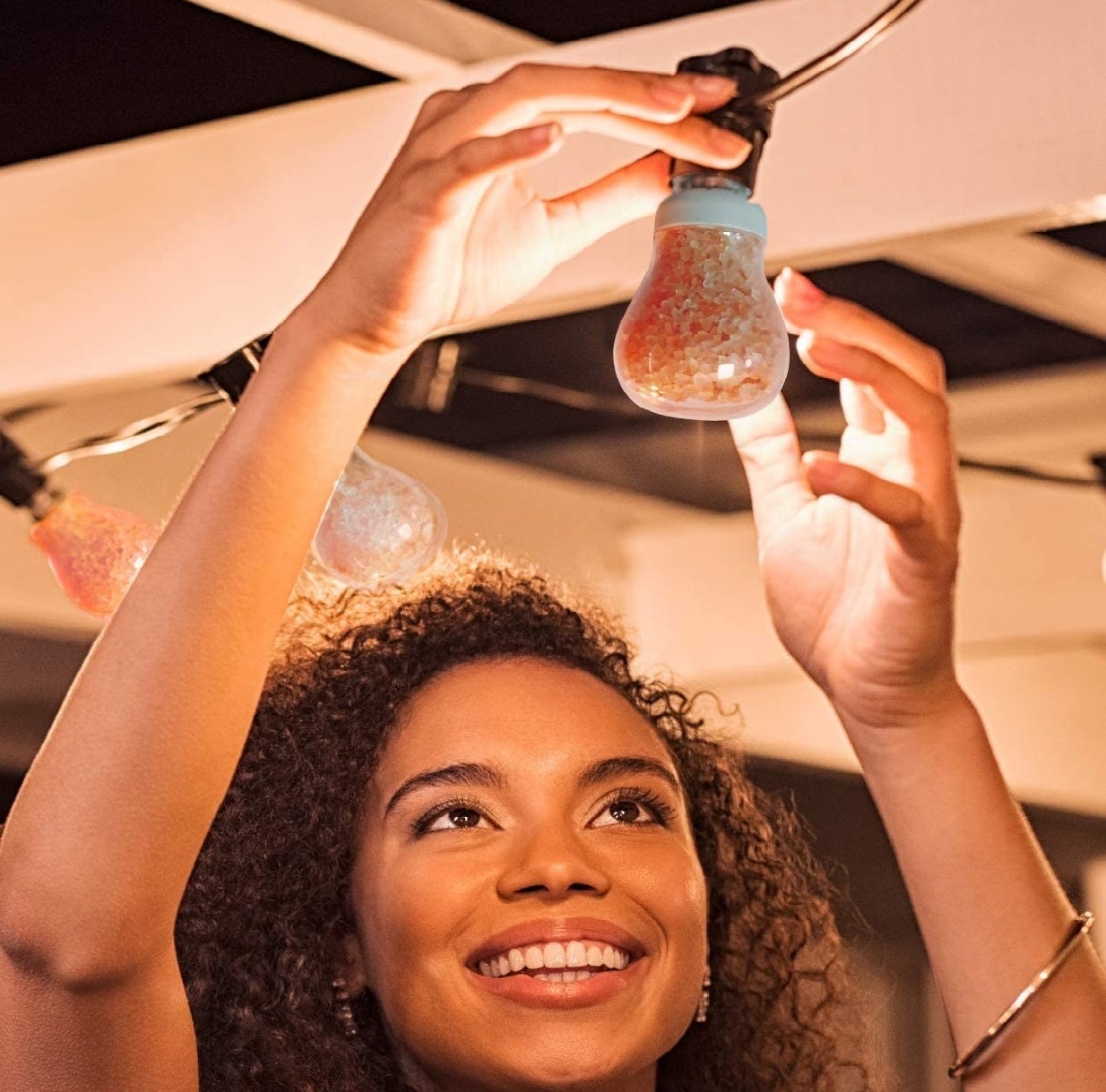 a smiling person installing a lightbulb filled with himalayan salt