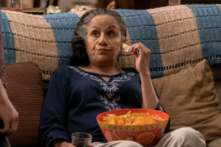 Abuelita sitting in her chair eating crisps.