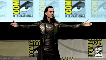 tom hiddleston dressed as loki, standing in character with his arms open at comic con