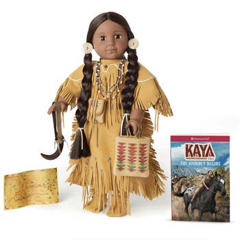 kaya doll in traditional indigenous dress with accessories, a book, and a map