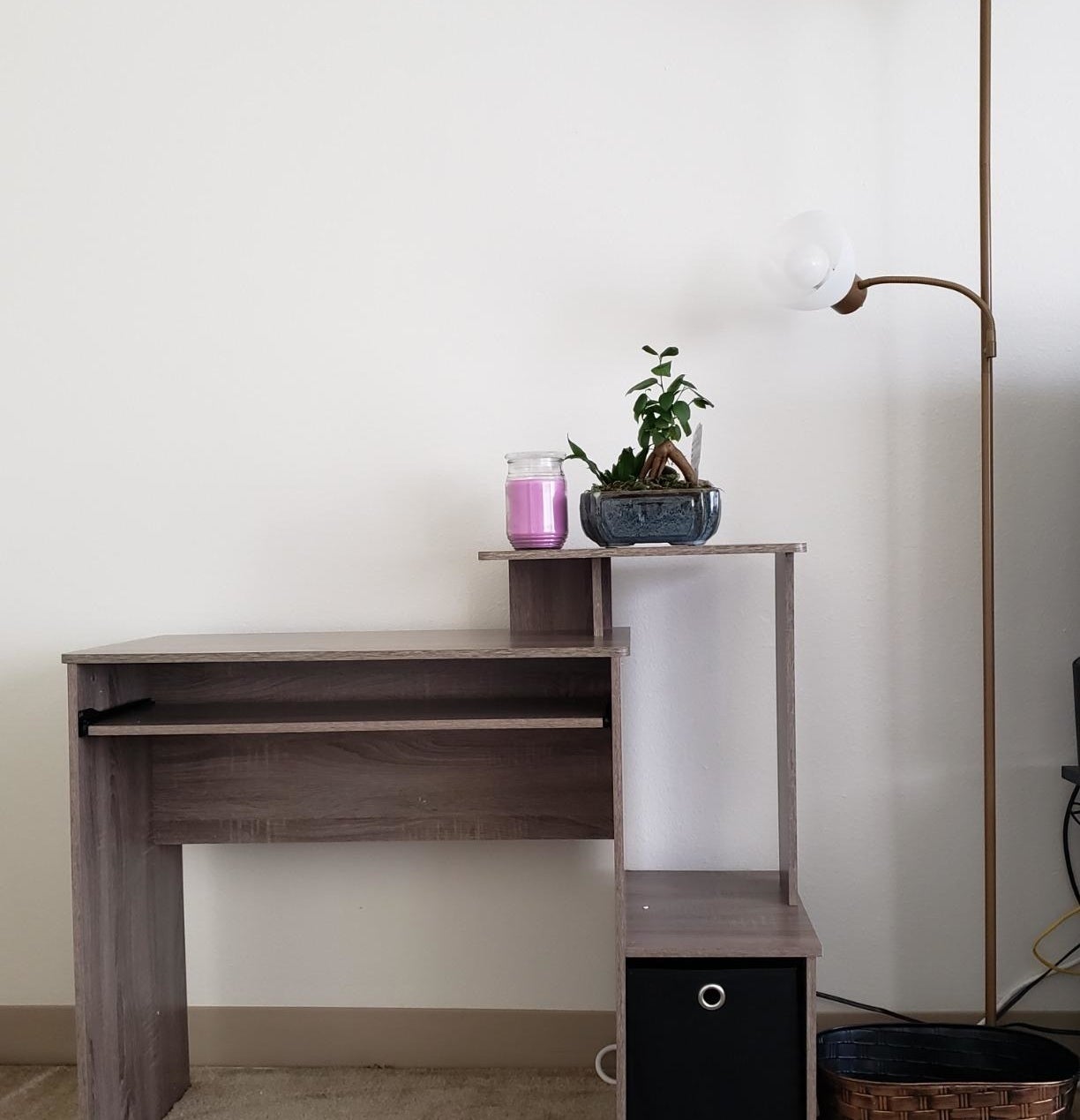 Reviewer image of brown desk with candle and plant on top of shelf