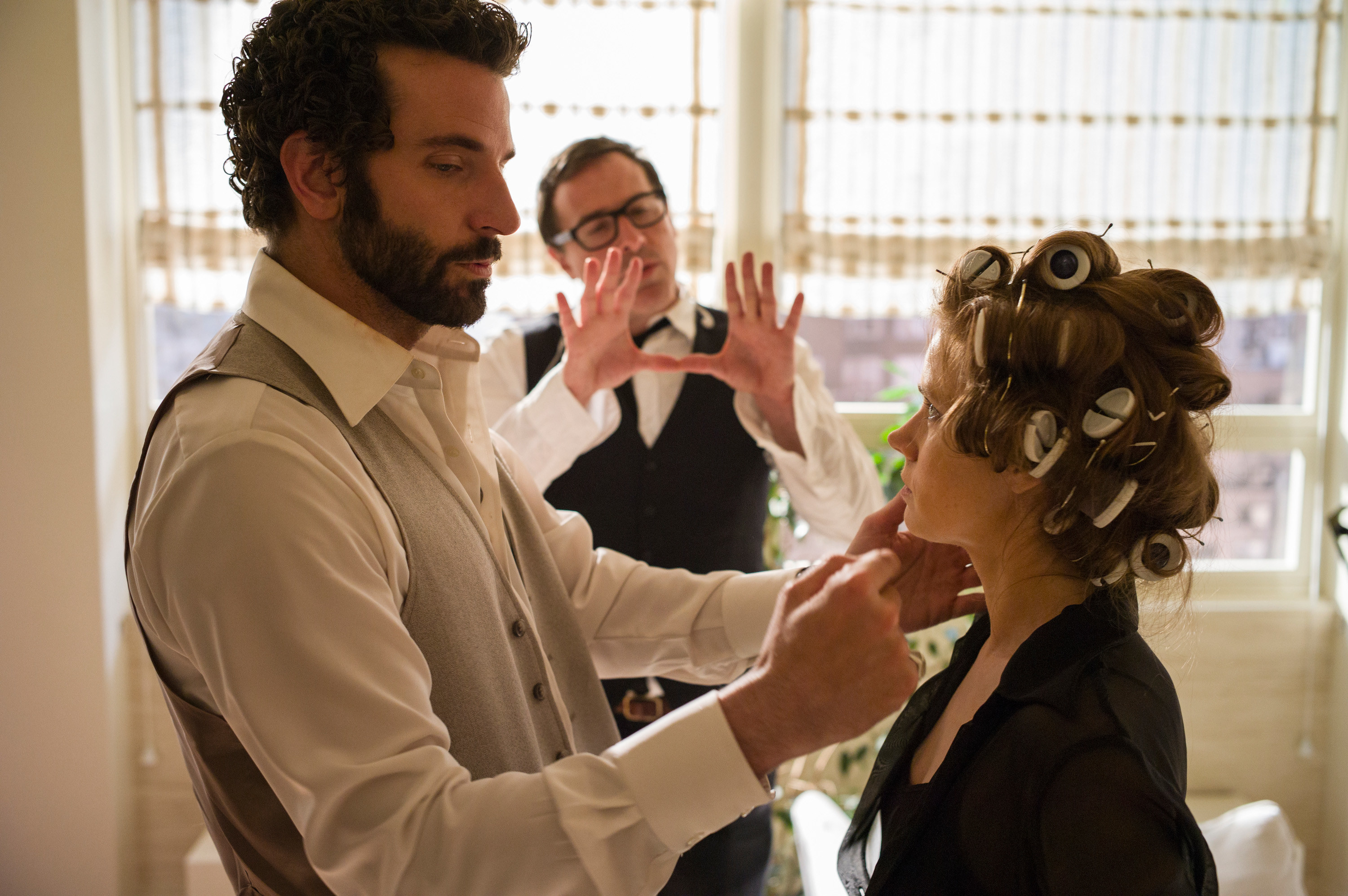 Russell directing Bradley Cooper and Amy Adams during a scene