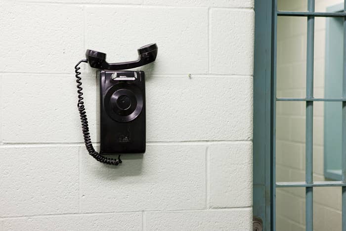 A phone on the wall of a prison building next to a cell